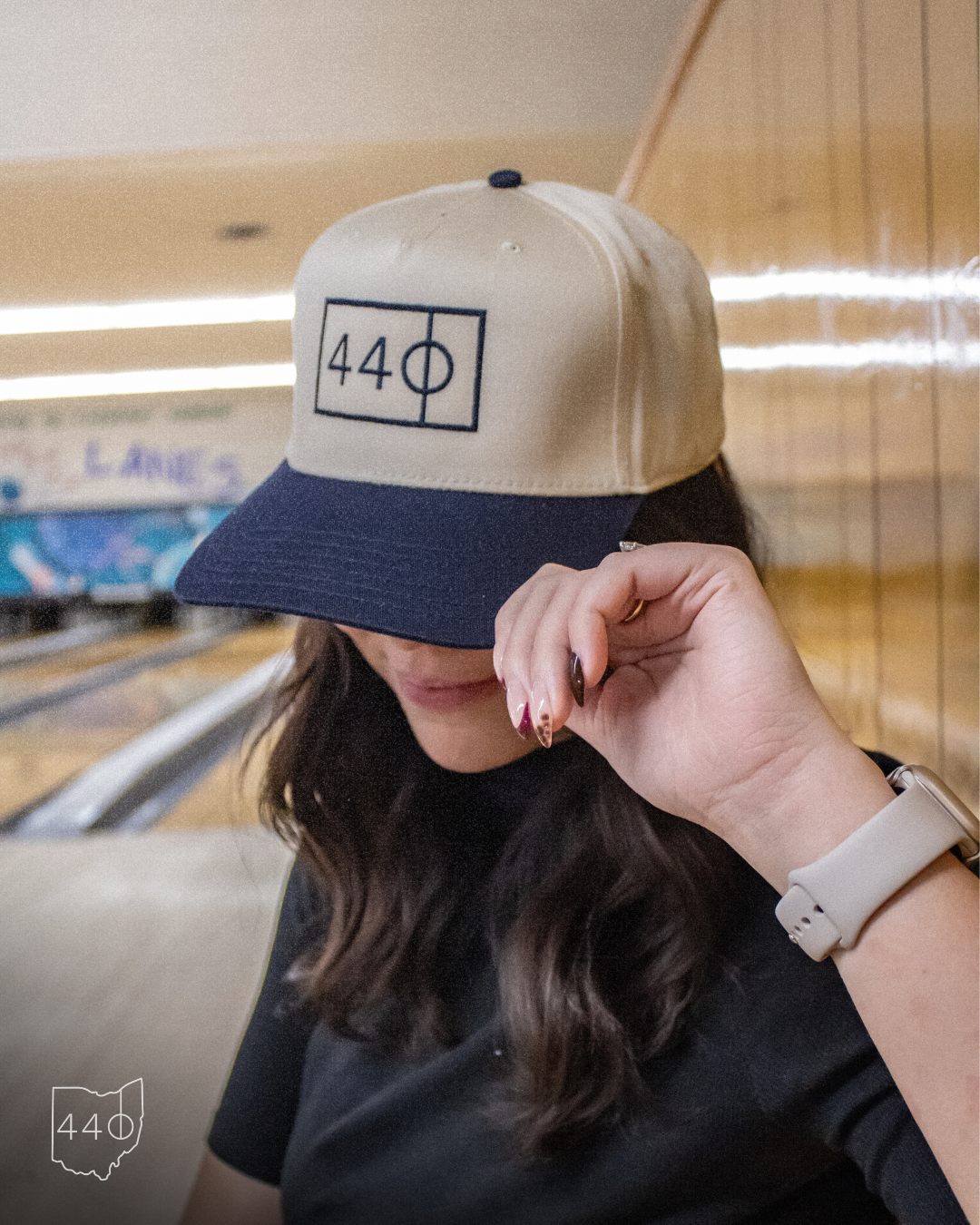 Woman wearing a tan and navy cap with a 