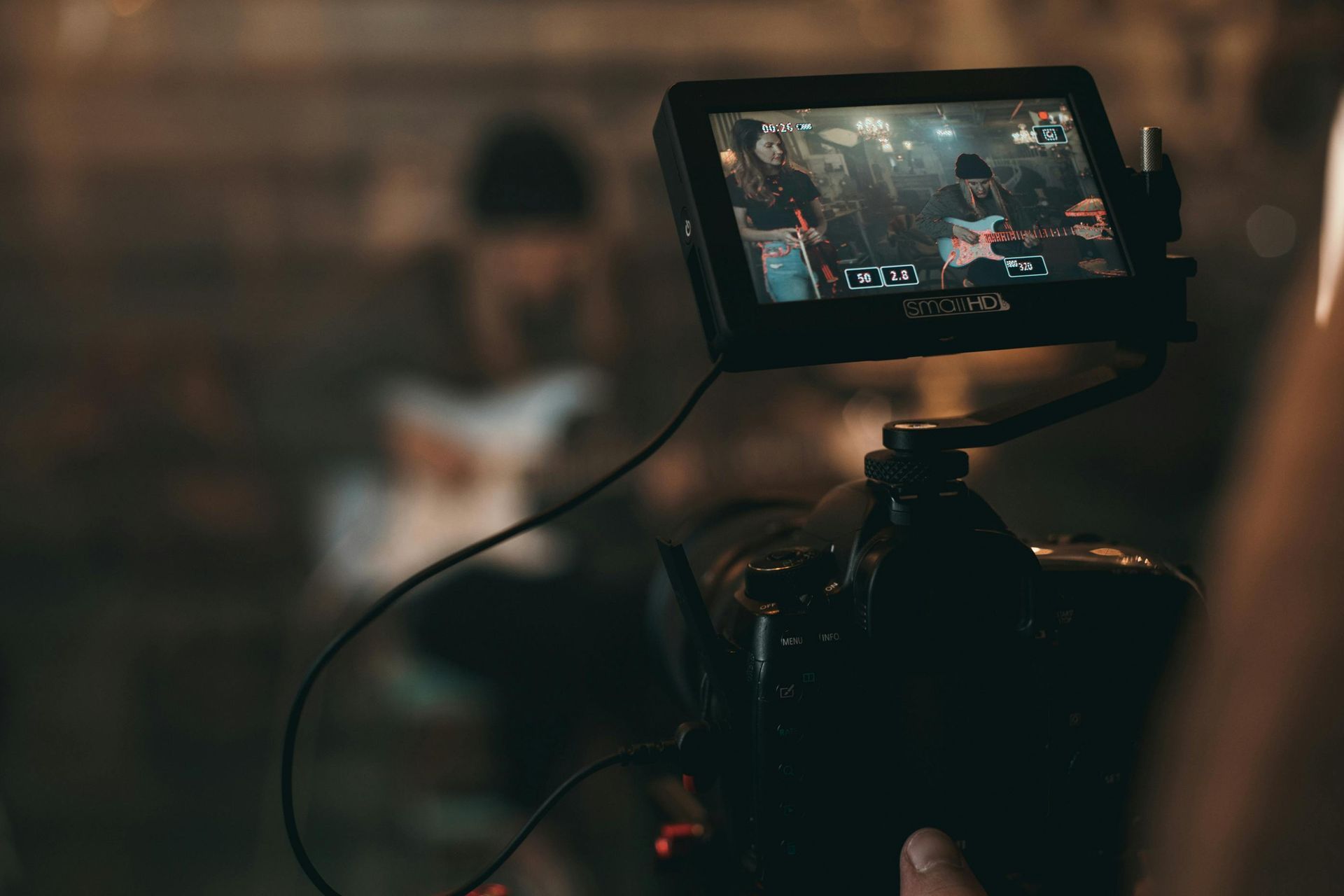 Camera filming a band playing live, showing the screen with the performance in view.