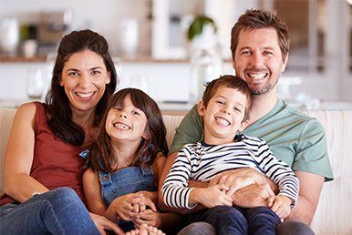 Happy Family Sitting on a Sofa — White Bear Lake, MN — Reibel Heating & Air Conditioning
