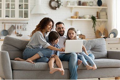 Happy Family With Kids Sit on Couch — White Bear Lake, MN — Reibel Heating & Air Conditioning