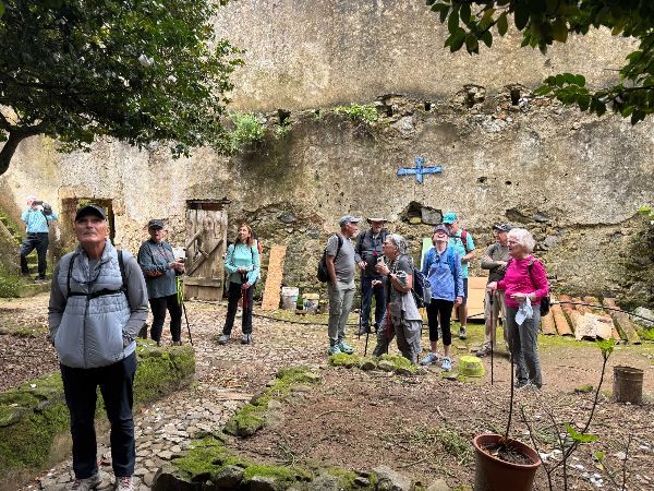 Group of people exploring ruins outdoors, some holding walking sticks.
