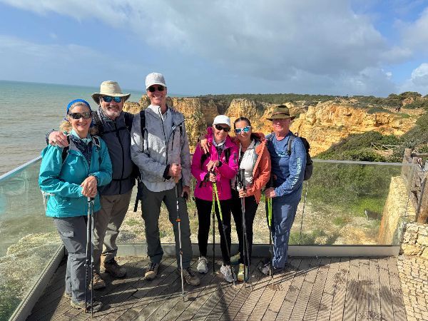 Group of people with hiking poles, by the ocean, posing for a photo.