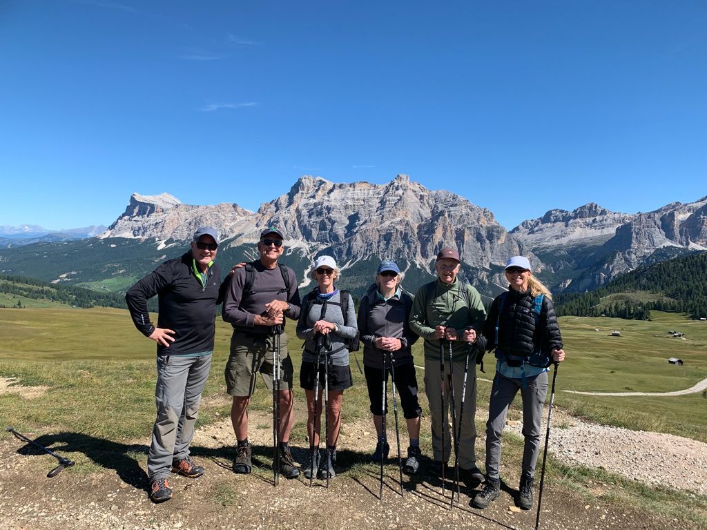 Group of hikers posing with mountain backdrop on a sunny day.