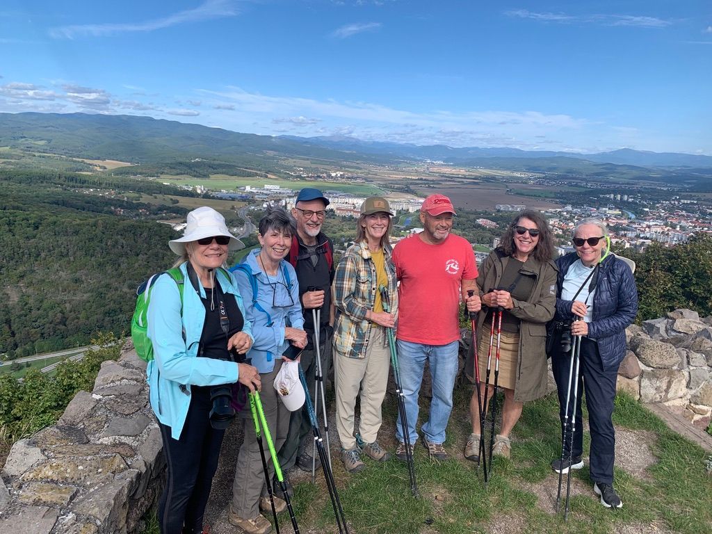 Group hikes on a gravel path up a grassy hillside, with ski lift in the background.