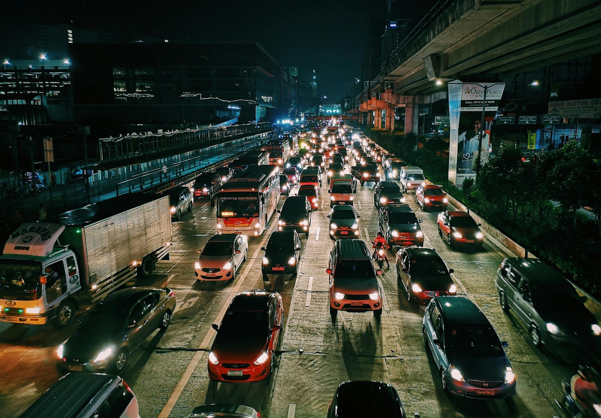Coches en tráfico intenso por la noche. Las luces de la ciudad se reflejan en la carretera.