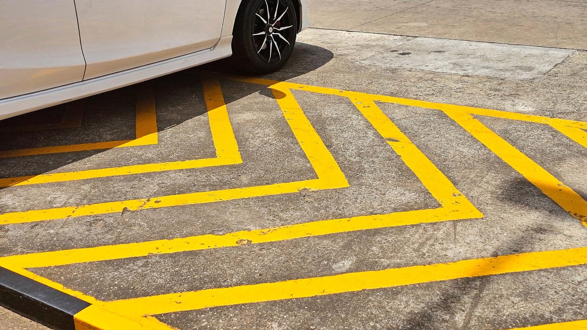 A white car is parked in a handicapped parking space