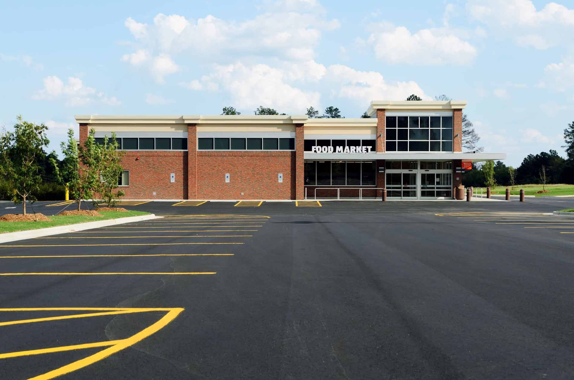 An empty parking lot in front of a brick building that says photo market