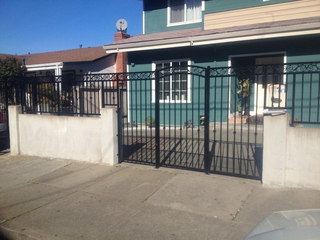 A wrought iron gate is in front of a house