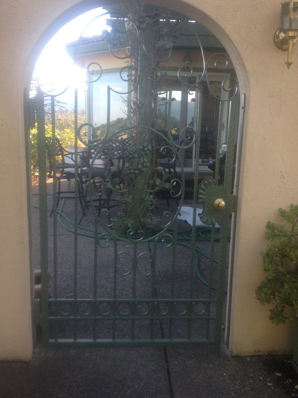 A wrought iron gate leading to a patio with chairs and umbrellas