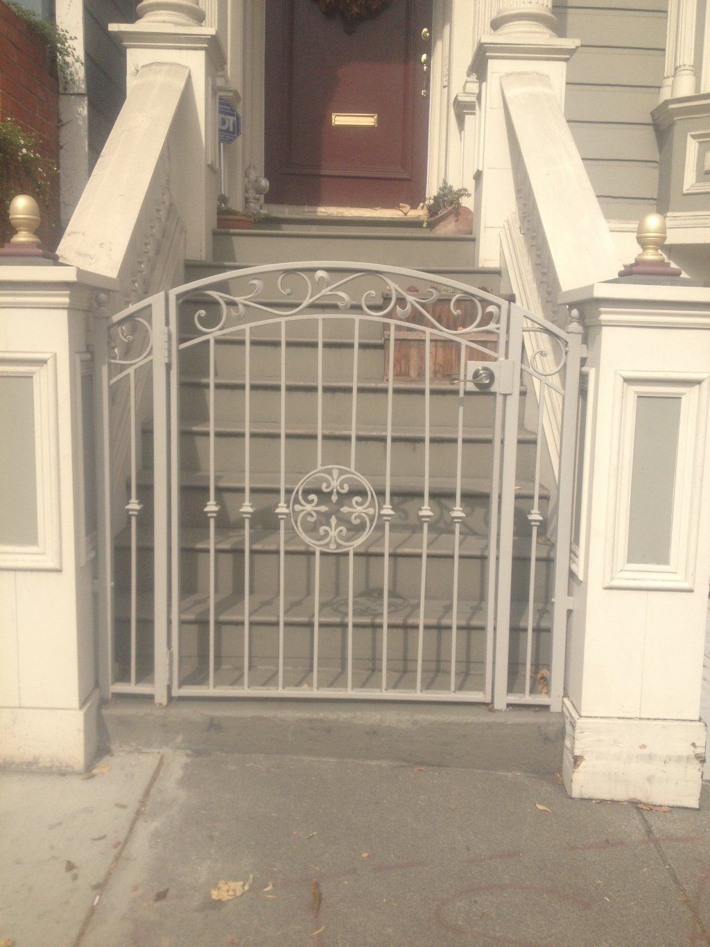 A white gate is in front of a house with stairs leading up to it.