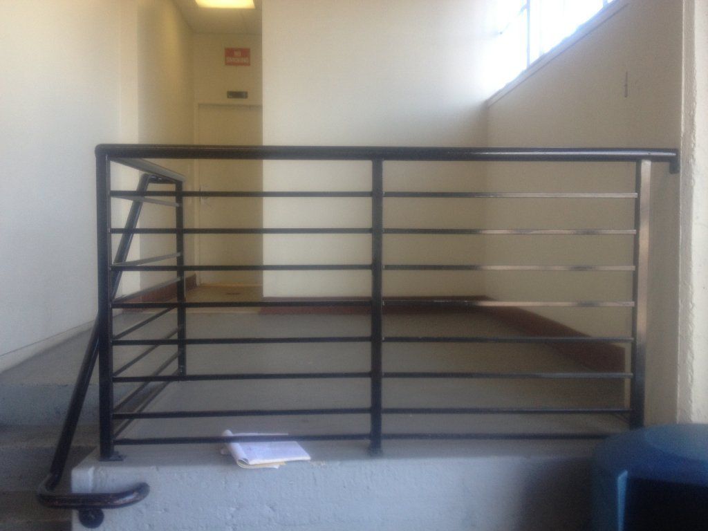 An empty hallway with a black railing and stairs