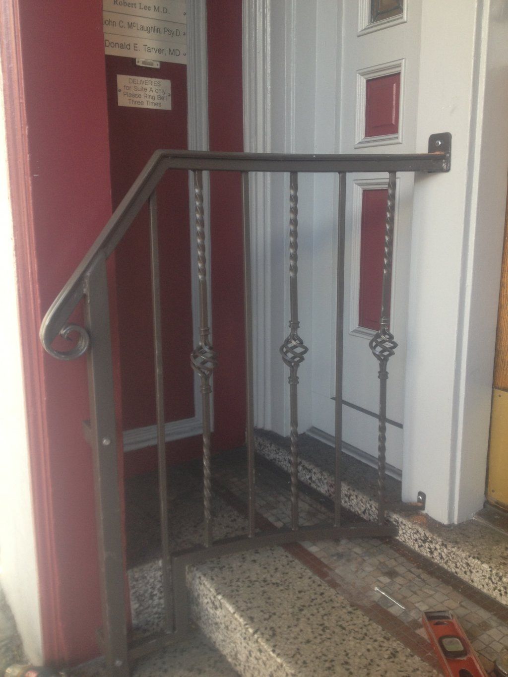 A wrought iron railing is being installed in front of a door.