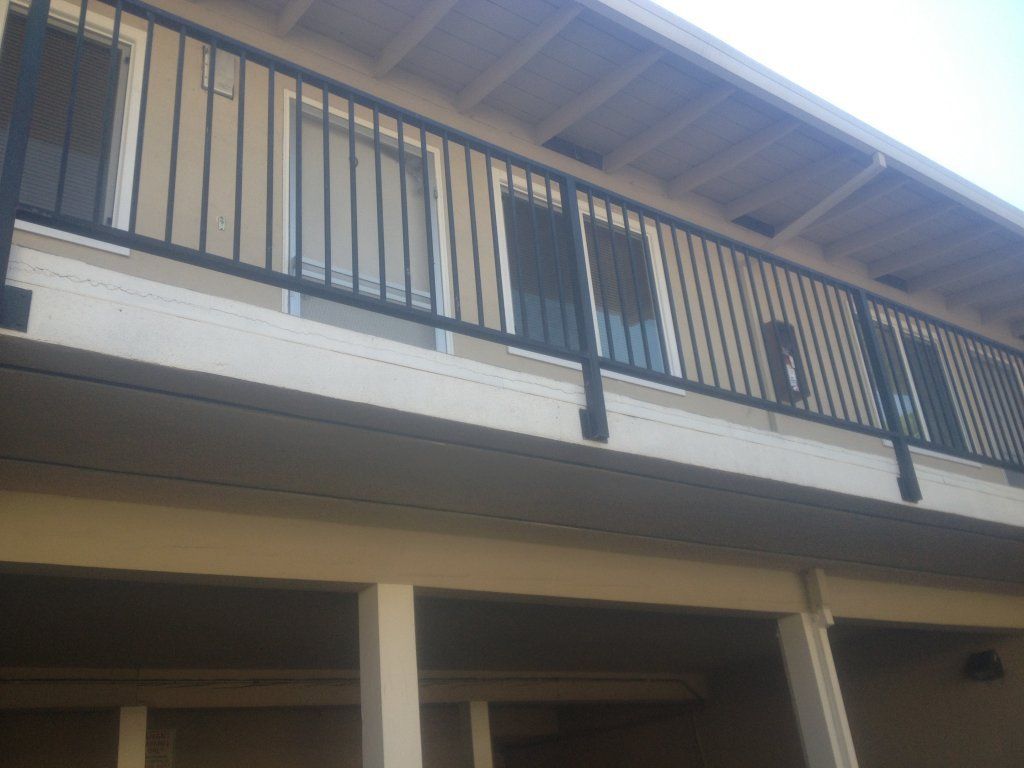 A balcony with a black railing on the side of a building