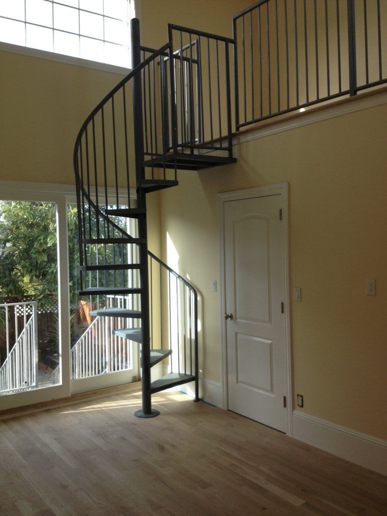 An empty room with a spiral staircase leading to the second floor