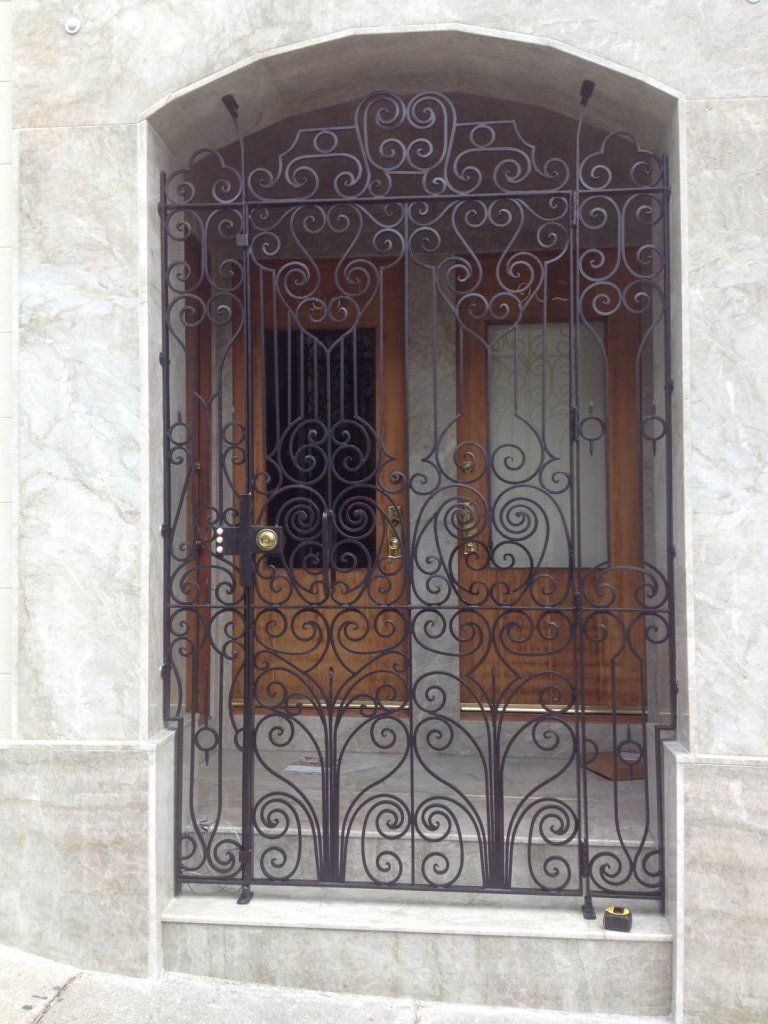 A wrought iron gate is surrounding a wooden door.