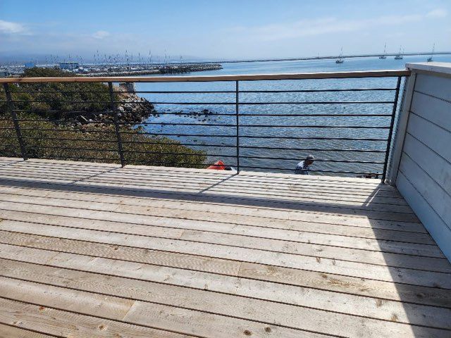 A wooden deck with a metal railing overlooking a body of water.