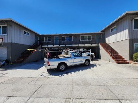 A white truck is parked in front of a building with stairs.