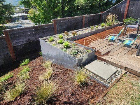 A garden with a wooden deck and a fence surrounding it.