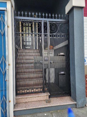 A wrought iron gate leading to a building with stairs behind it.
