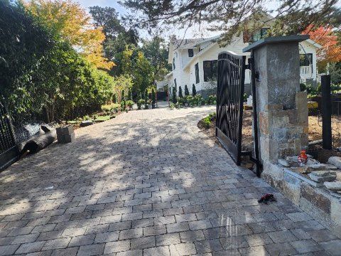 A brick driveway leading to a house with a gate.