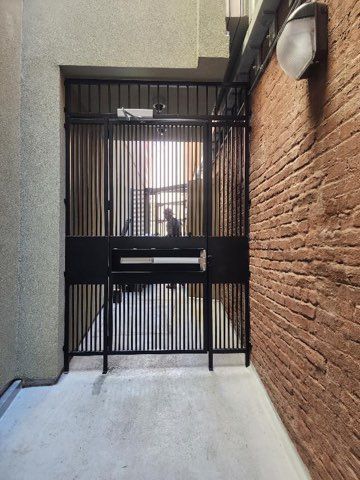 A brick wall with a black gate in the middle of it.