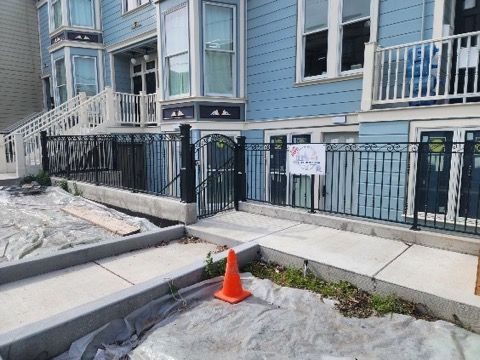 A blue building with a fence and a orange cone in front of it.