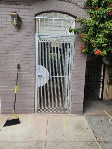 A brick building with a metal gate and a broom on the sidewalk.
