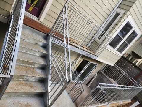 A set of stairs leading up to a balcony on the side of a house.
