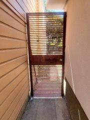 There is a gate in the middle of a hallway between two buildings.