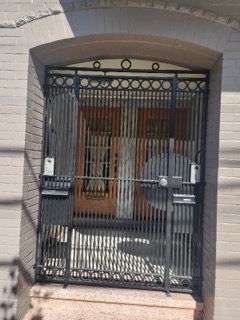 A wrought iron gate is surrounding the entrance to a building.
