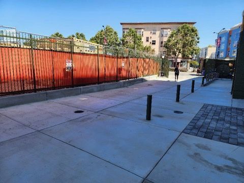 A concrete walkway with a red fence and a building in the background