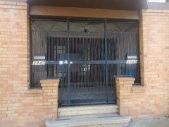 A brick building with a wrought iron gate and stairs leading to it.