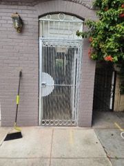 A metal gate is sitting on the sidewalk in front of a brick building.