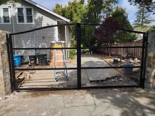A black gate is sitting in front of a house.