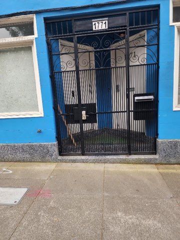 A blue building with a black gate and a mailbox in front of it.