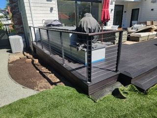 A deck with a stainless steel railing and a grill on it.