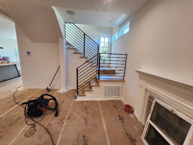 A room with stairs and a vacuum cleaner on the floor.