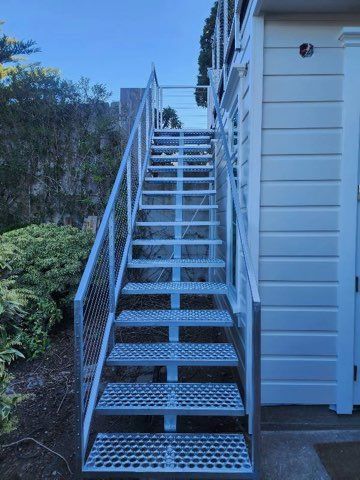 A set of metal stairs leading up to a white house.
