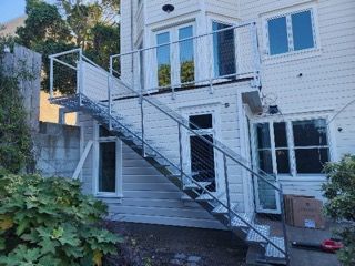 A white house with a metal staircase leading up to the second floor.