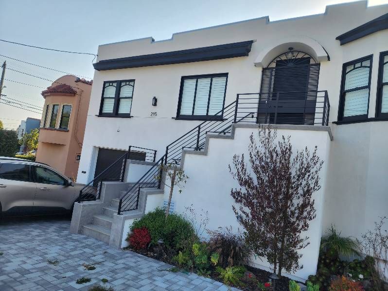 A white house with stairs and a car parked in front of it