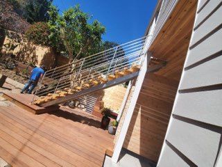 A man is standing on a wooden deck next to a staircase.