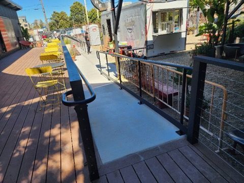 A wooden deck with a metal railing and a ramp leading to it.