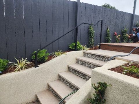 A set of stairs leading up to a fence with a black railing.