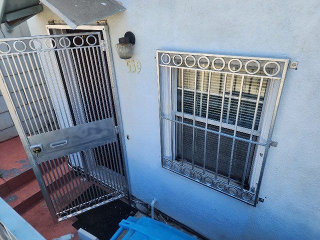 A blue car is parked in front of a building with a gate and window