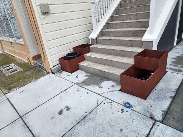 A set of stairs with planters on the sidewalk in front of a house.