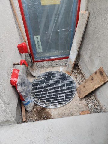 A manhole cover is sitting on the ground next to a door.