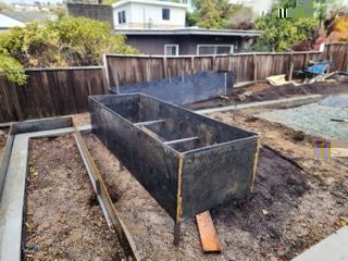 A large metal box is sitting in the dirt in a backyard.