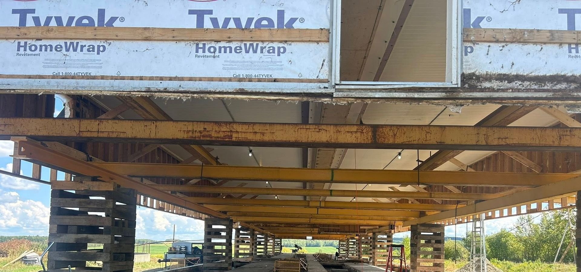 Une maison est surélevée grâce à des supports en bois. On aperçoit le Tyvek et le Homewrap.
