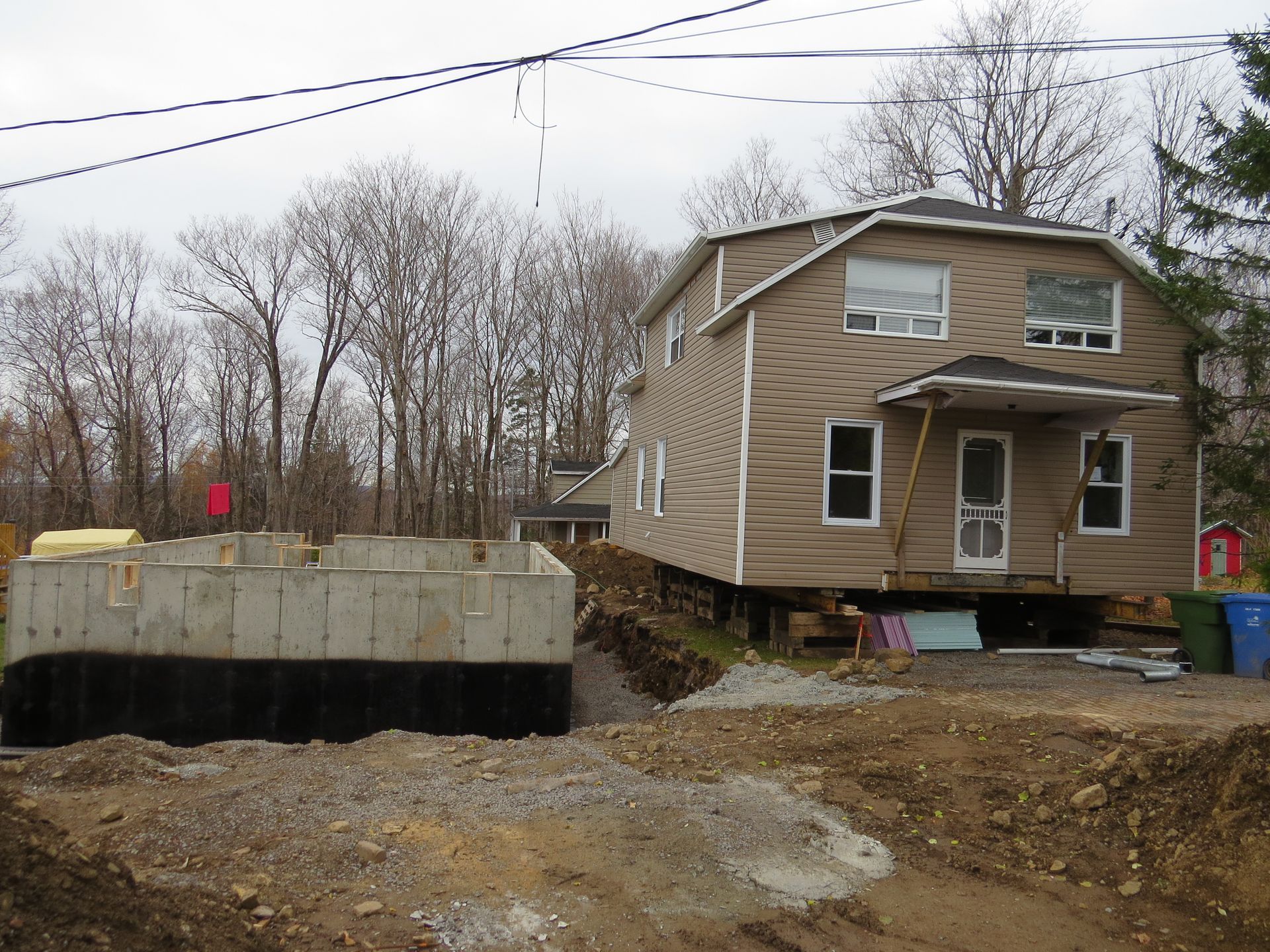Une maison est déplacée à côté de nouvelles fondations en béton sur un chantier de construction.