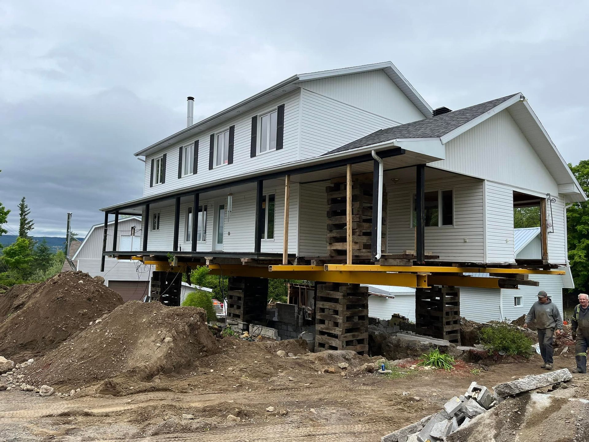 Maison blanche surélevée sur des supports en bois, chantier de construction.
